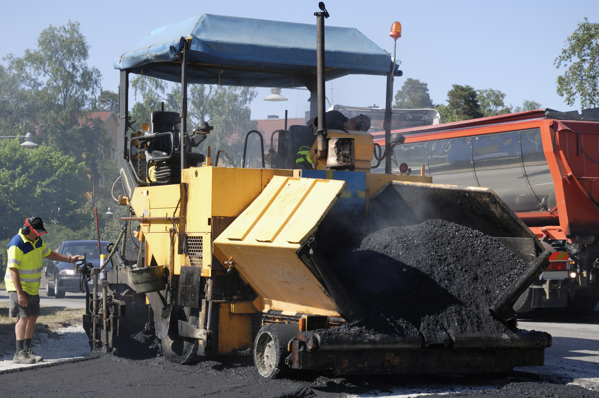 Asphalt roller in yellow and black colors at work.